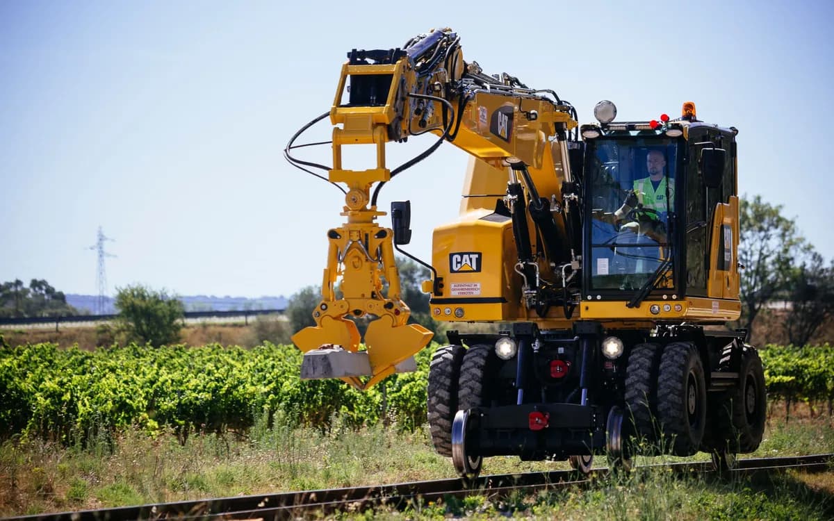 Pelle rail-route sur la voie, essieux rail sortis, conducteur en cabine